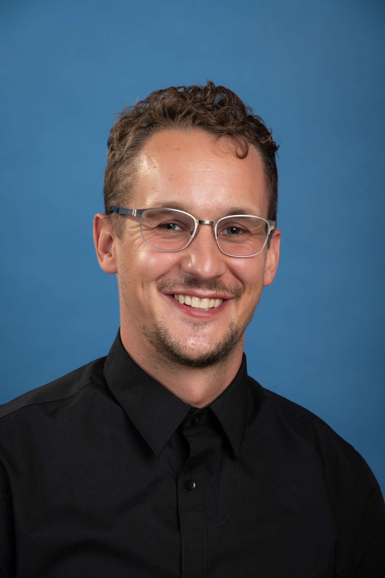 Eric, smiling, in a black shirt and glasses